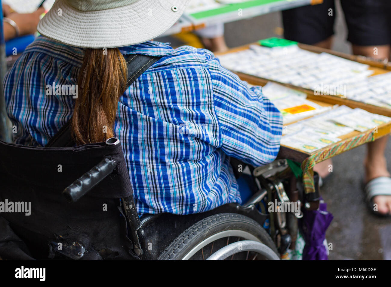 Girls sit the wheelchair and sell government's lottery at a street