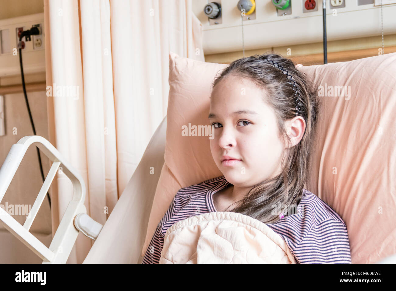 Asian American tween girl lying in hospital bed, health care concept Stock Photo