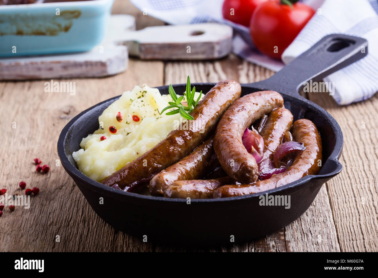 Sausage and onion casserole served with potato mash in cast iron skillet on rustic wooden table