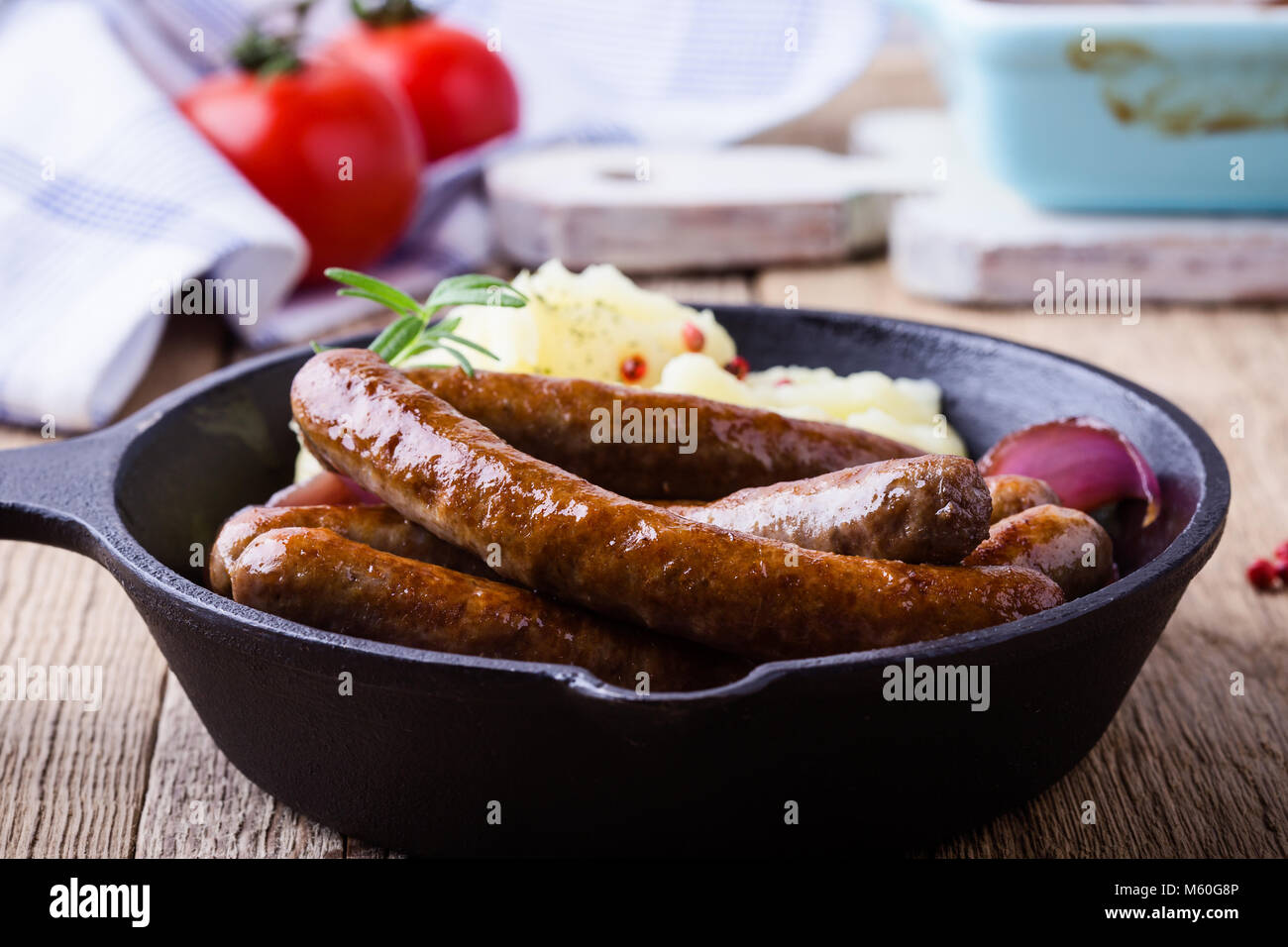 Sausage and onion casserole served with potato mash in cast iron skillet on rustic wooden table