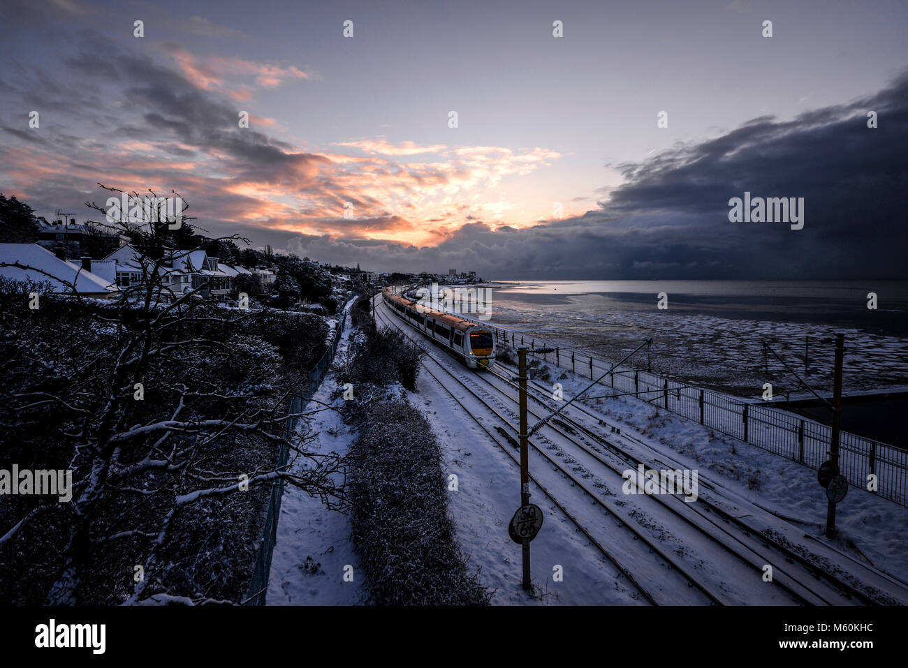 Train in snow. C2C railway train running through snow covered lines in Chalkwell near Southend on Sea, Essex at dawn next to the Thames Estuary Stock Photo