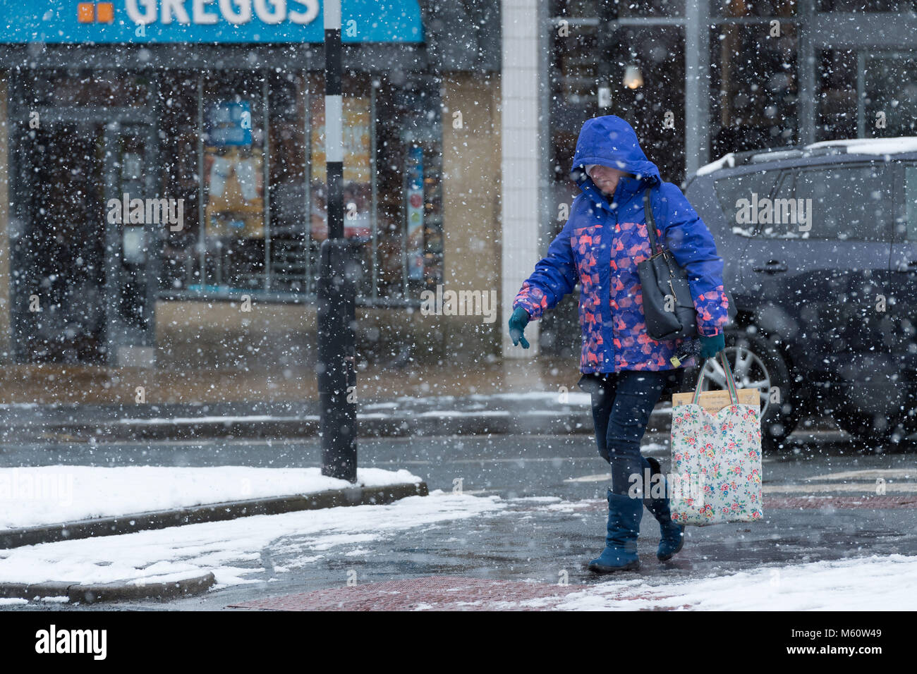 Ilkley, West Yorkshire. 27th Feb, 2018. UK Weather: A woman in Ilkley,  head bowed, dressed in winter clothing with hood up & wearing gloves & boots, is braving the falling snow whilst walking past shops on Brook Street. 27th February 2018, Ilkley, UK Credit: Ian Lamond/Alamy Live News Stock Photo