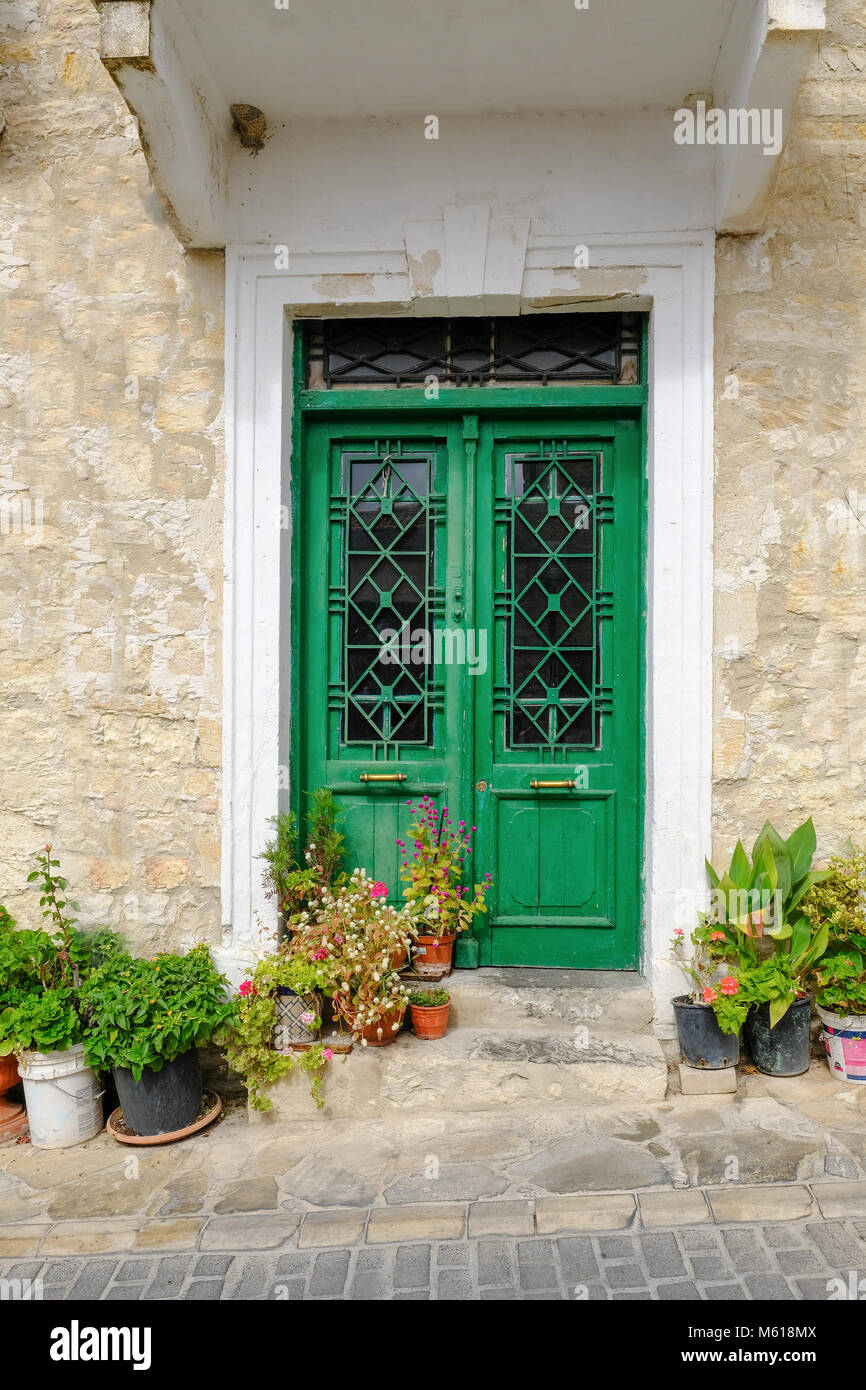 Typrical Cypriot style double green doors with windows and patterned metal grills. Stock Photo