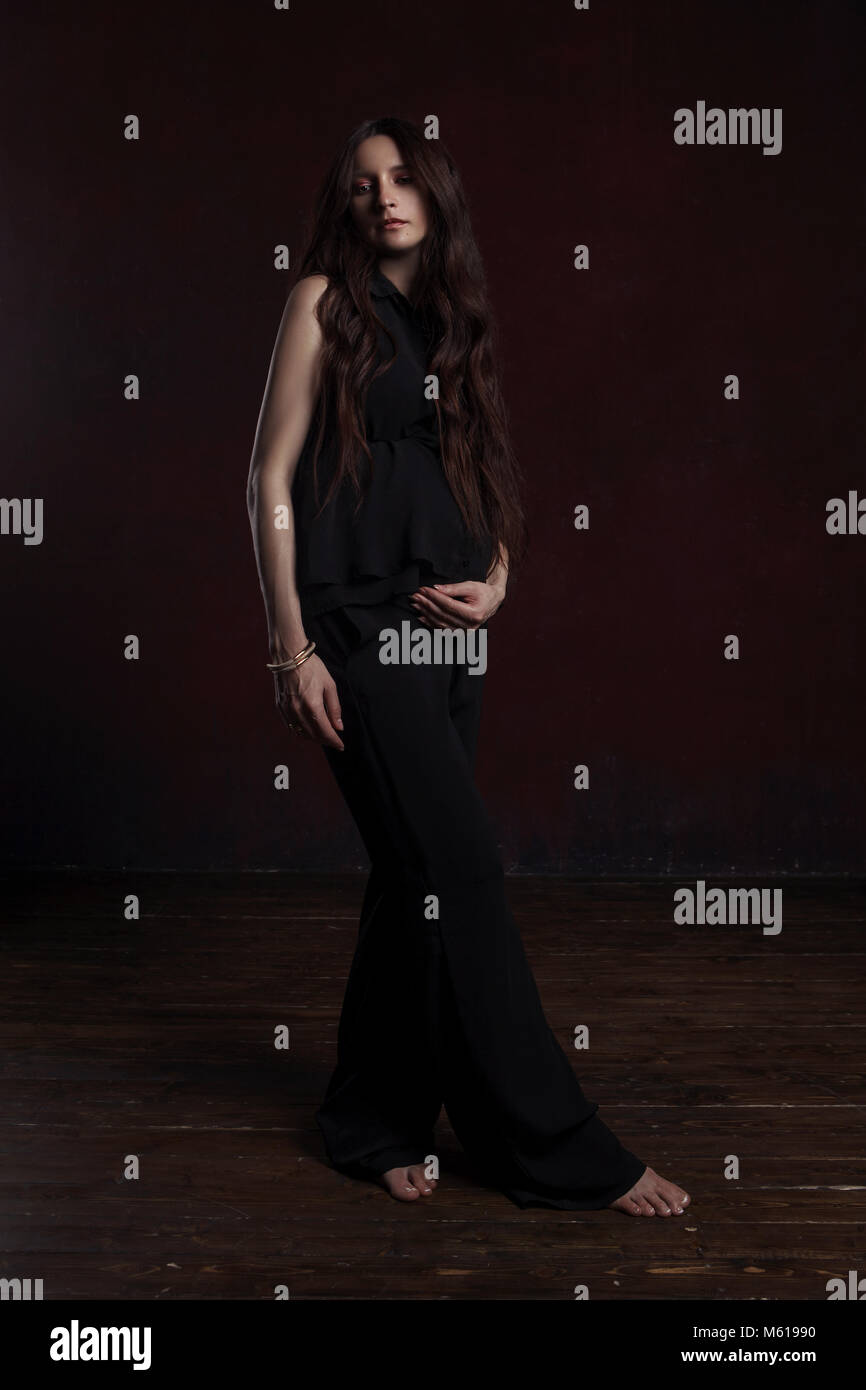 studio photoshoot of pregnant female on dark background in black clothes Stock Photo