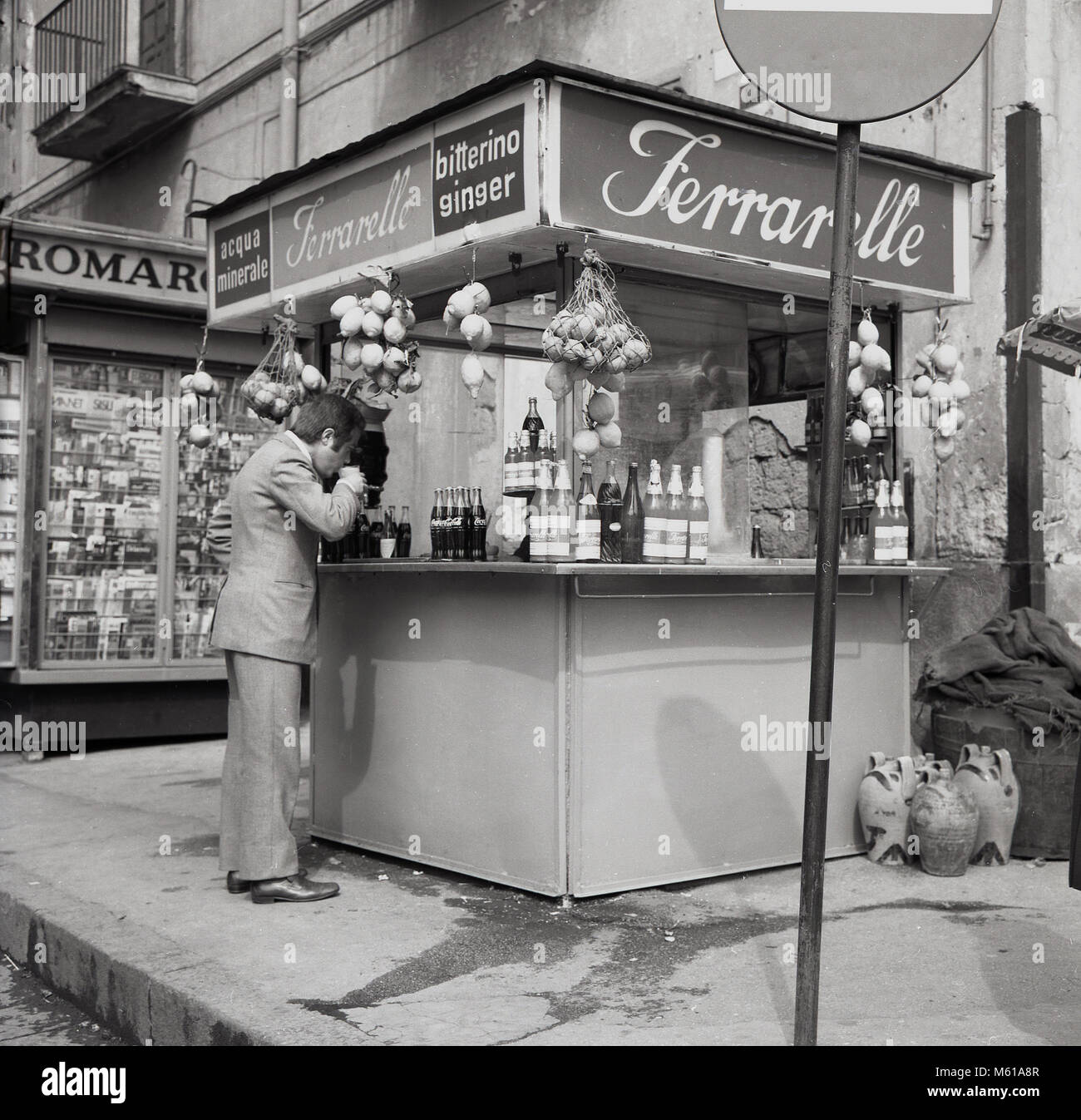 1950s, historical, Naples, Italy, a man drinking at a street kiosk of  Ferrarelle, an Italian sparking mineral water. The water from Val d'Assano,  Naples has a unqiue flavour coming as it does