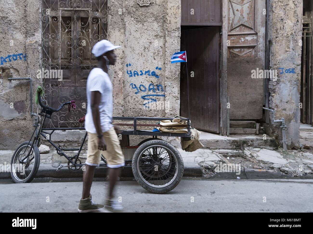 A young man walks through an alley in Havana's old town, where a cargo bike is parked. (16 November 2017) | usage worldwide Stock Photo