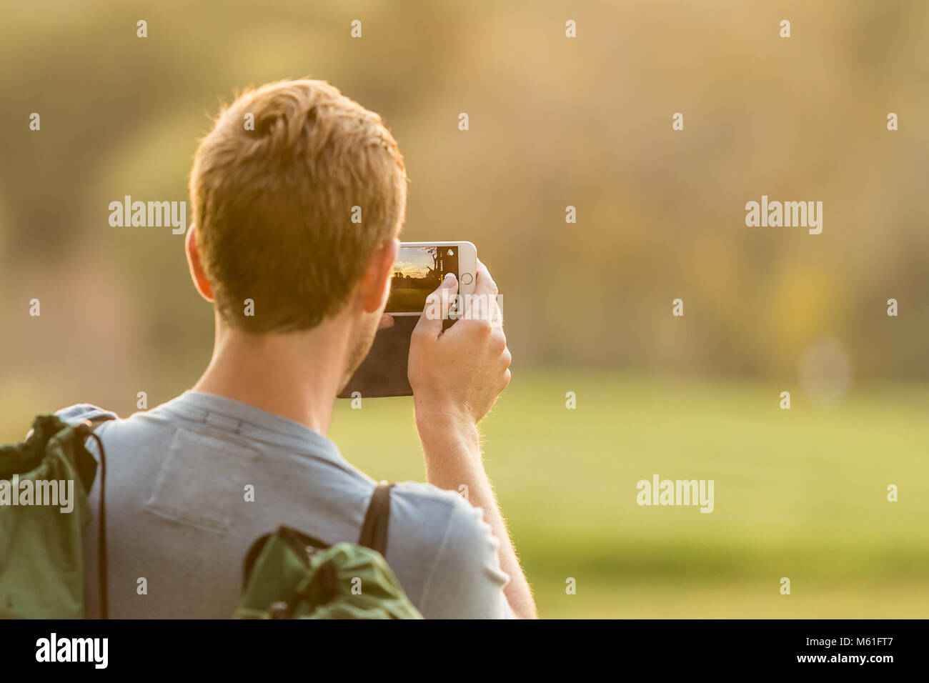 Young man taking a photo on his phone in a park Stock Photo