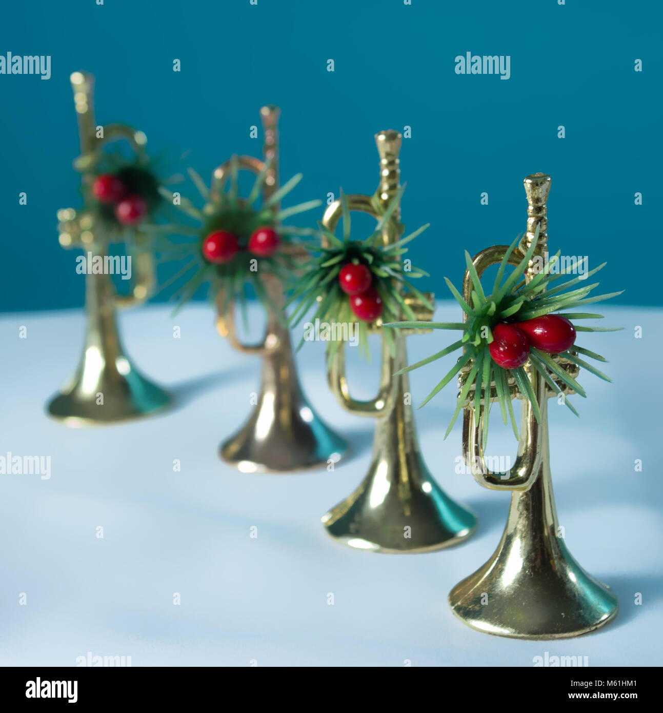 The four trumpets festively decorated with a blue and white background. Christmas still life for musicians. Focused on the first trumpet. Stock Photo