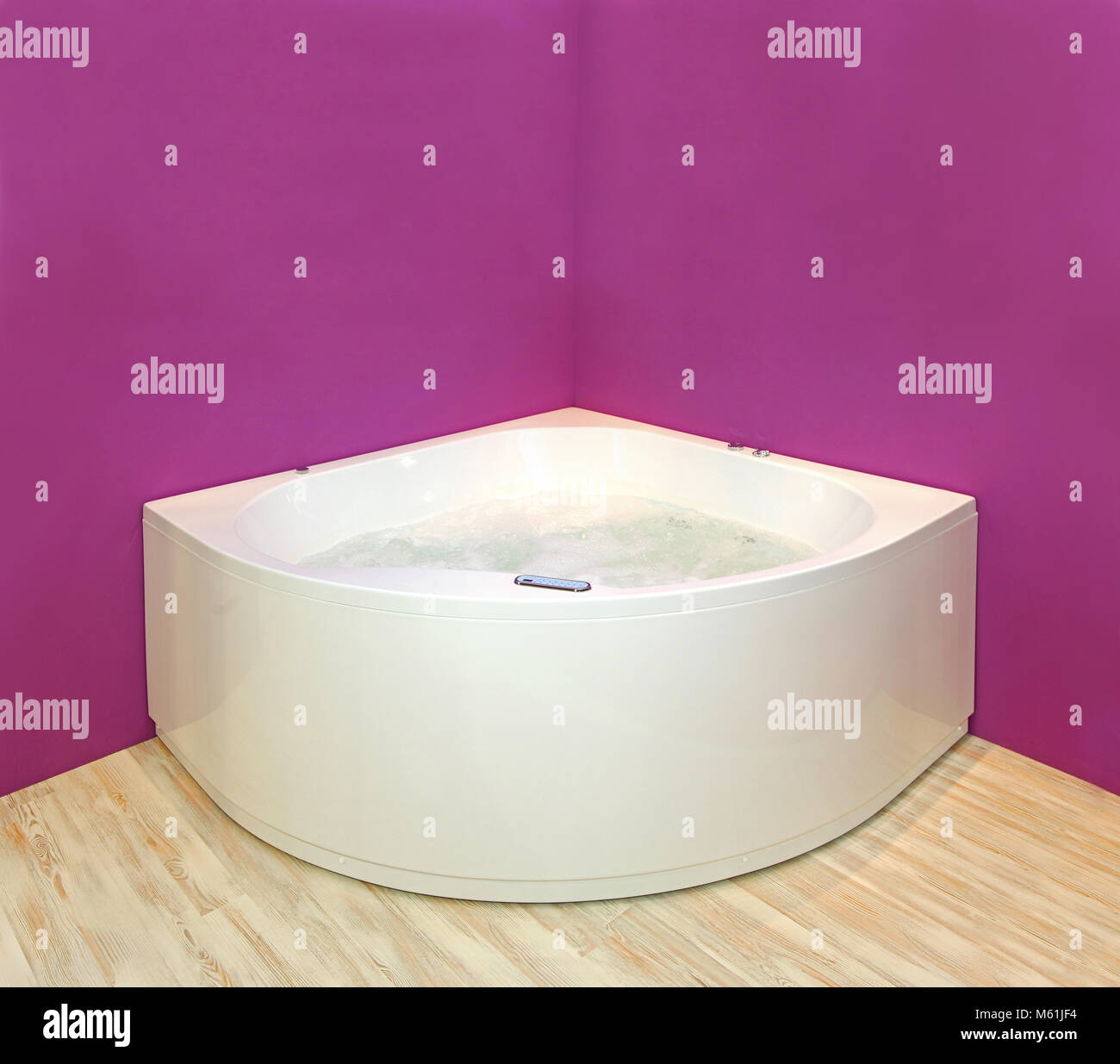 Modern corner hydromassage bathtub with pink wall interior Stock Photo