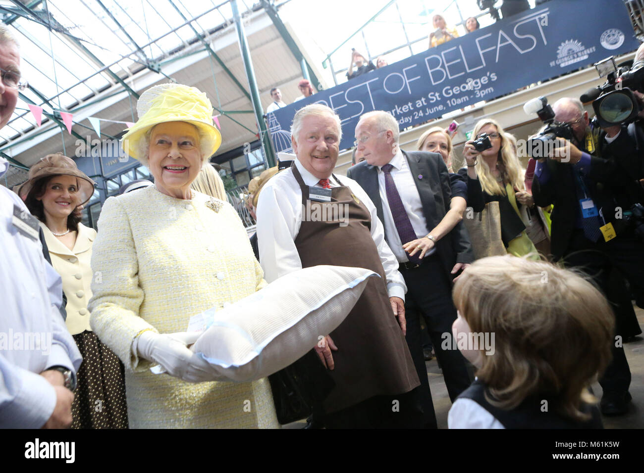 Queen Elizabeth II is presented with a cushion for Prince George by 3 year old Jack Morgan at St George's indoor market on June 24, 2014 in Belfast, Northern Ireland. The Royal party are visiting Northern Ireland for three days. Pool Photo/Paul McErlane Stock Photo