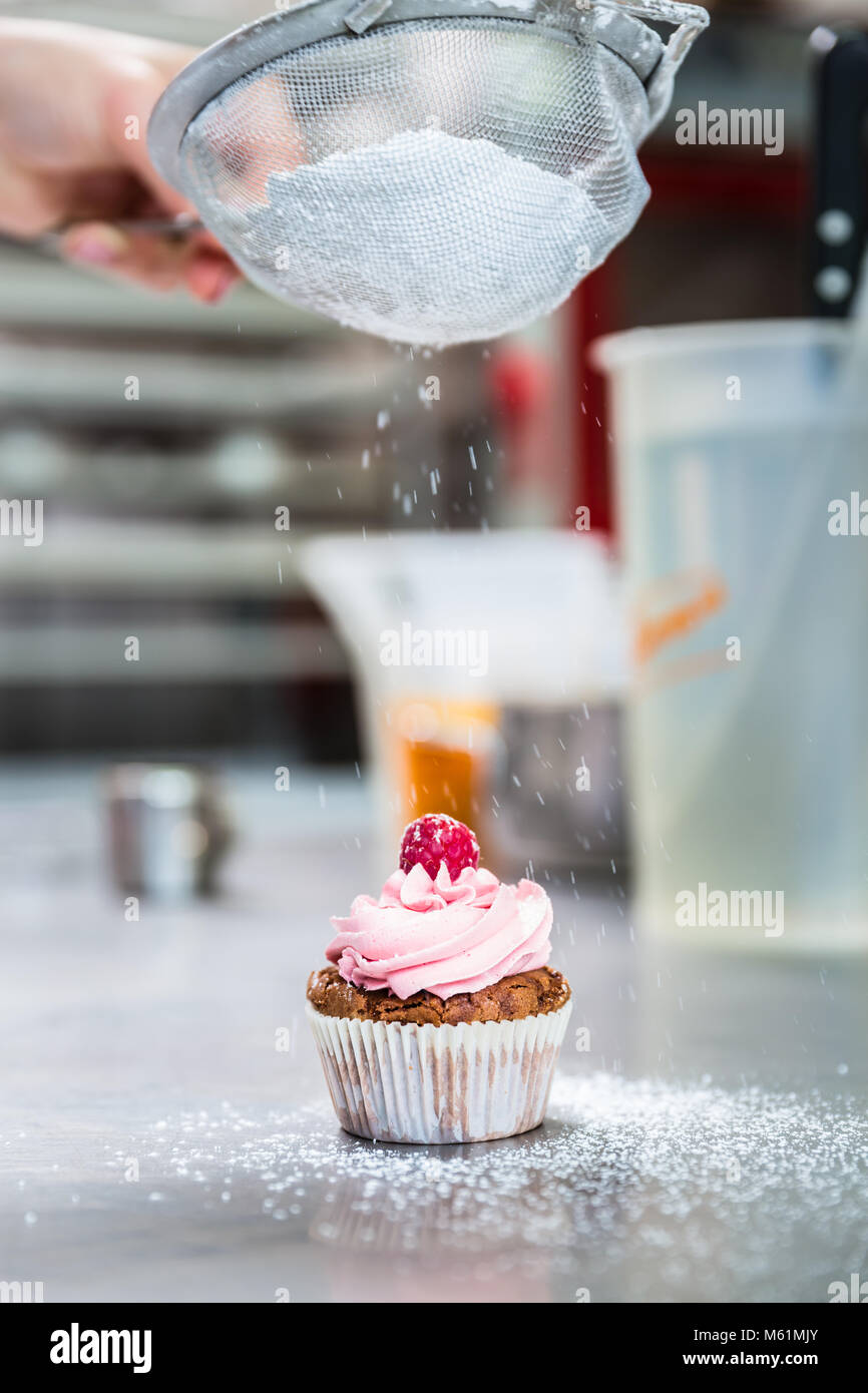 Woman in confectionary icing cupcakes with sugar Stock Photo