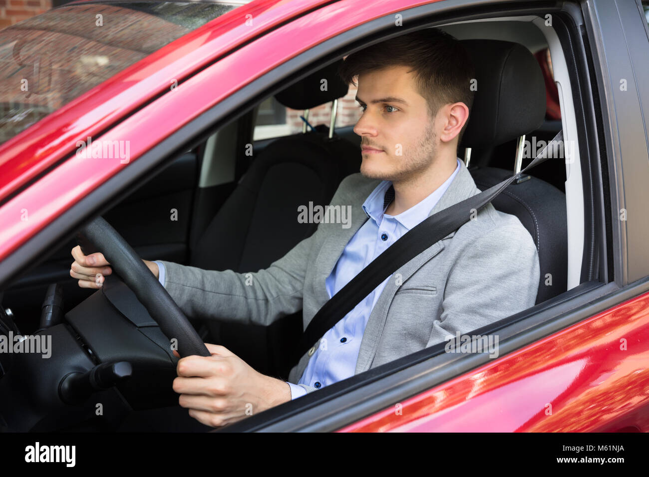 Close-up Of A Young Man Driving Red Car Stock Photo
