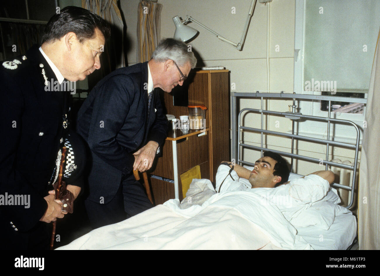 British Home Secretary Douglas Hurd visiting injured police officer in hospital following the Tottenham Riots on Broadwater Farm Estate in 1985. On the left is deputy commissioner of the Metropolitan Peter Imbert who later became Baron Imbert. Stock Photo