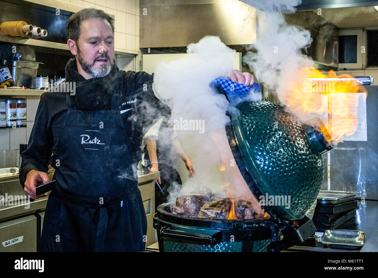 German 3 Michelin star chef Marco Müller with Big Green Egg. One of the secrets of tender beef brisket is the "reverse" order: first heat it in the oven at low heat and then grill it hot in its own smoke just before cutting it Stock Photo