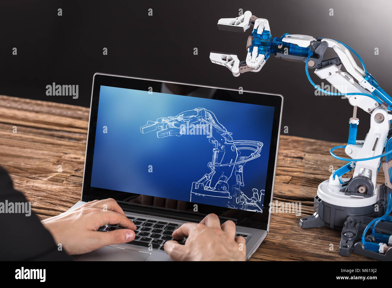 Close-up Of Businessperson Working On Design Of Industrial Robot Arm On Laptop Stock Photo