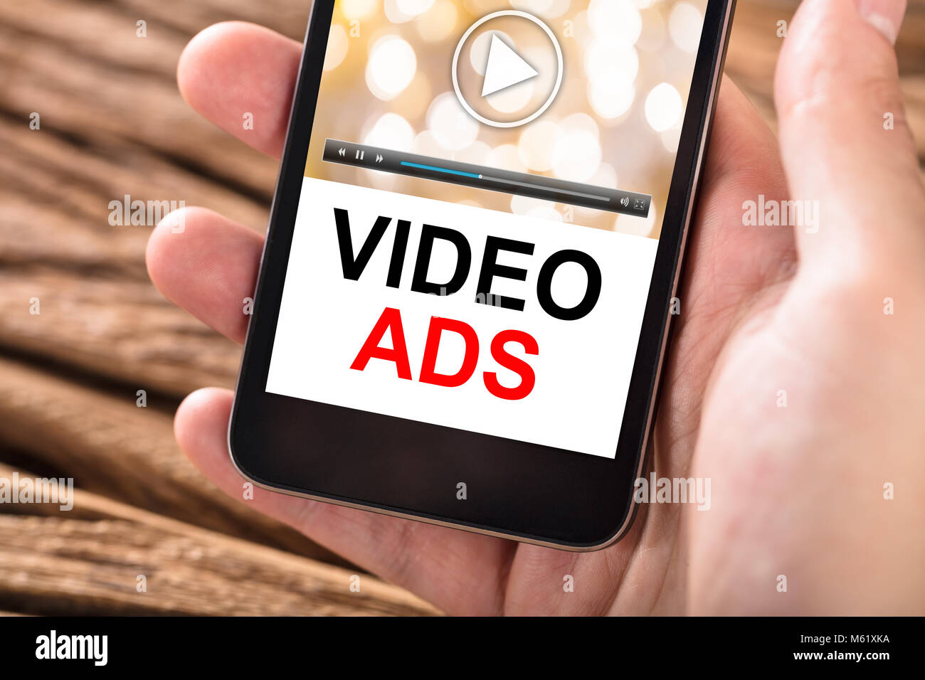 Close-up Of Person's Hand Holding Mobile Phone With Text Video Ads On Screen Stock Photo
