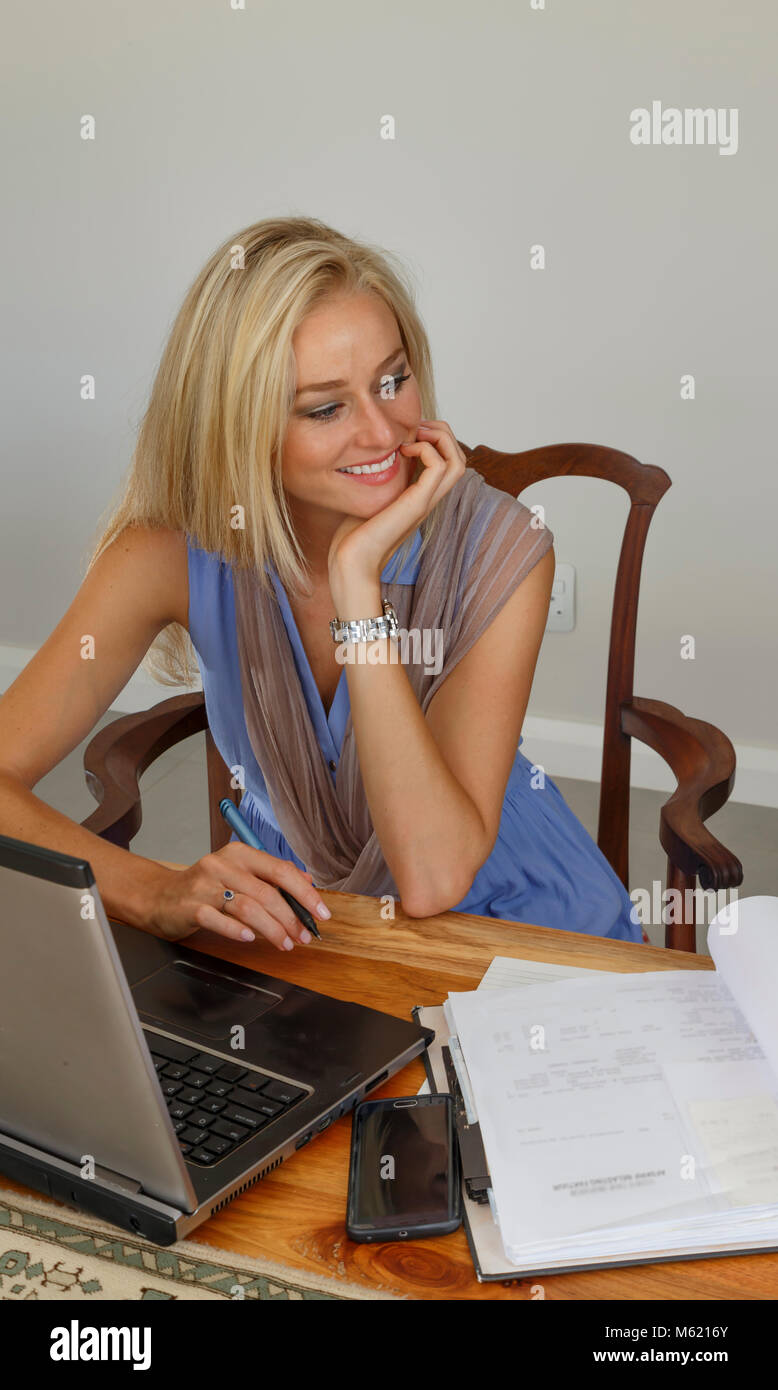 A smiling well dressed young adult woman working from home in a relaxed environment Stock Photo