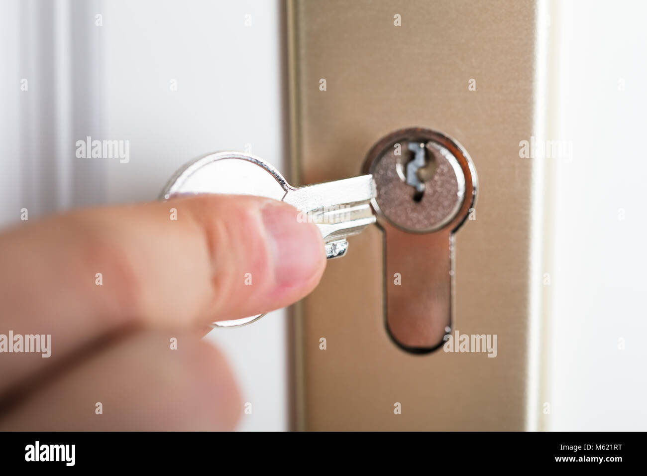 Close-up Of Person's Hand Holding Broken Key Inserting In Keyhole Stock Photo