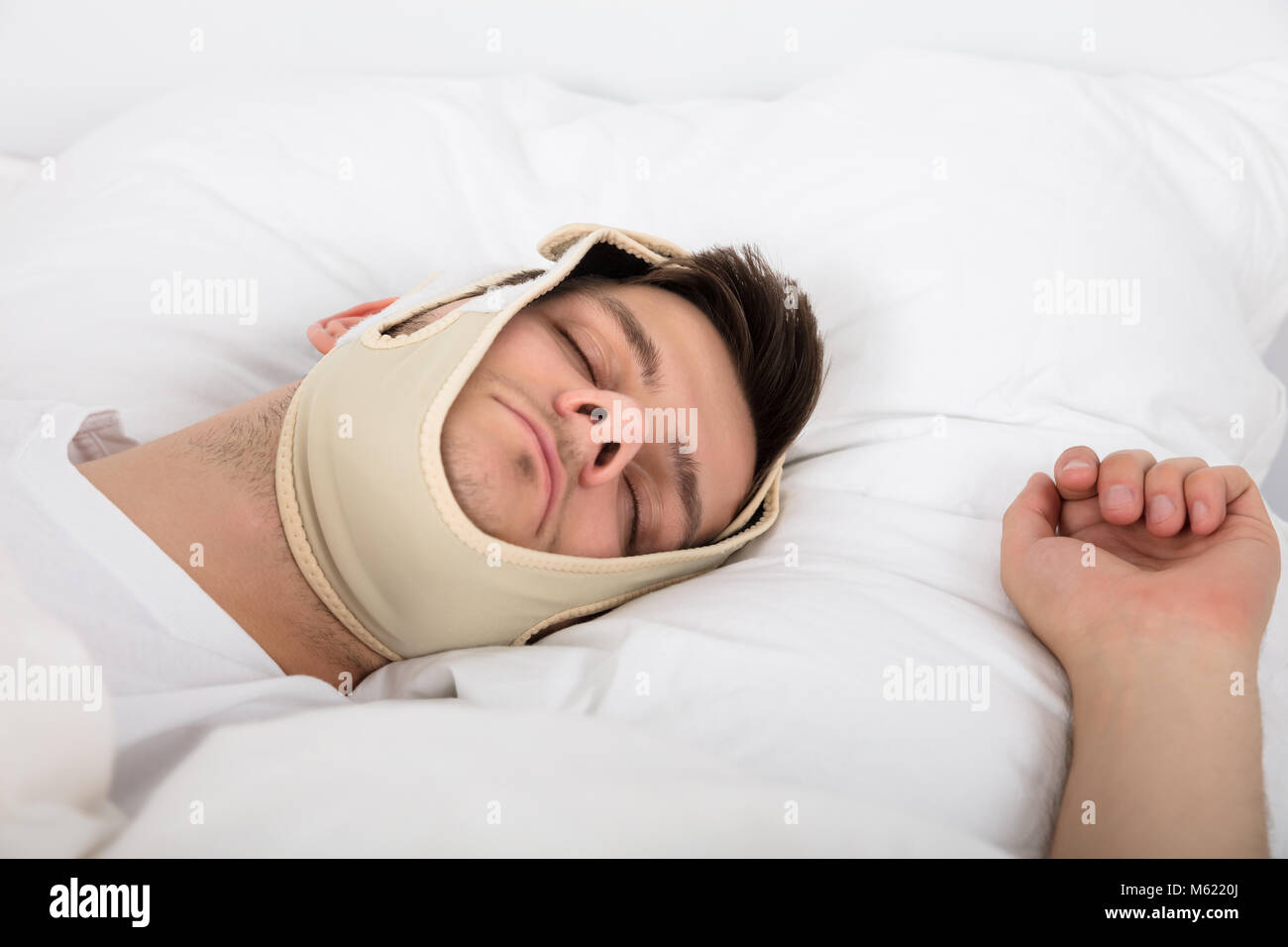 Young Handsome Man Sleeping With Anti Snoring Chin Strap On Head At