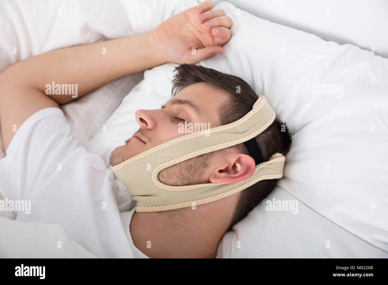 Young Handsome Man Sleeping With Anti Snoring Chin Strap On Head At