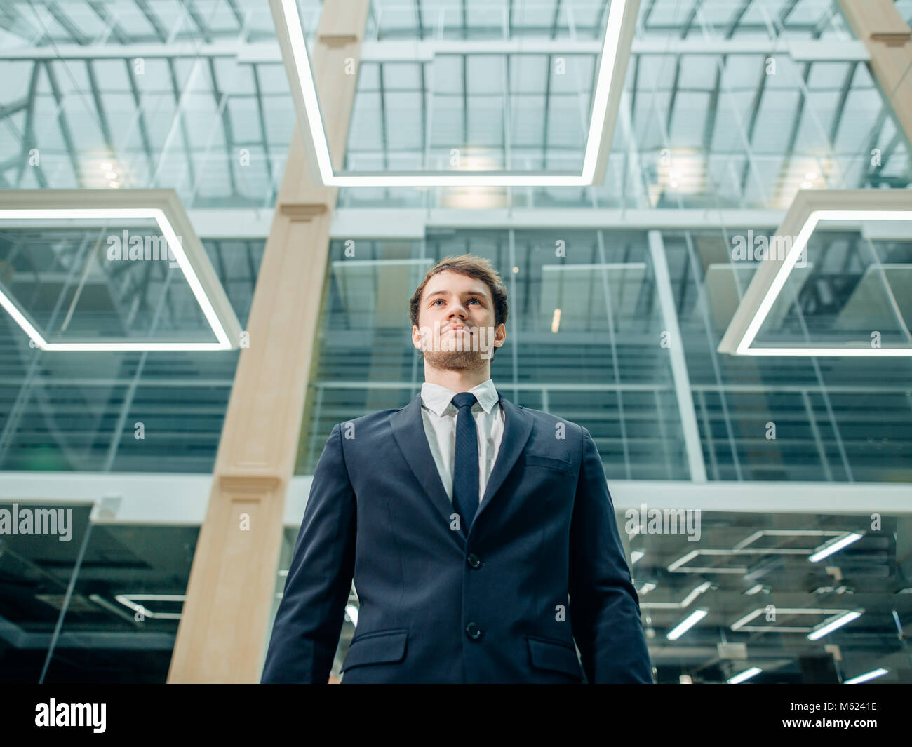 confident young businessman standing arms crossed, smiling, looking at ...