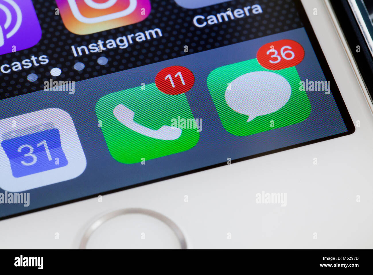 Notification badges (red dot) showing high number of missed calls and text messages on iPhone 5s home screen - USA Stock Photo