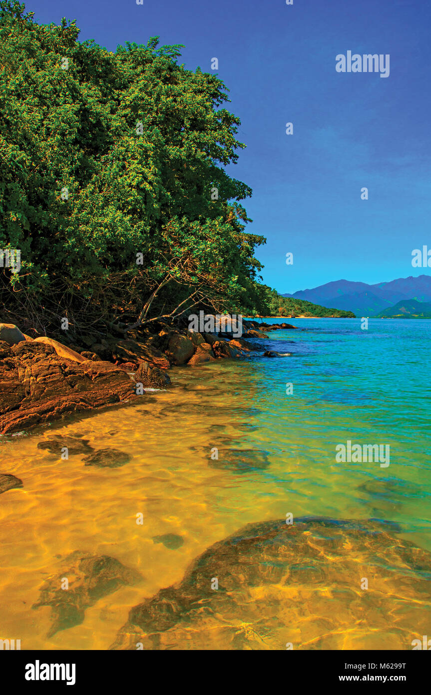 View of rocks, sea and forest on sunny day in Ilha do Pelado, a tropical beach near Paraty, an historic town totally preserved. Retouched photo Stock Photo