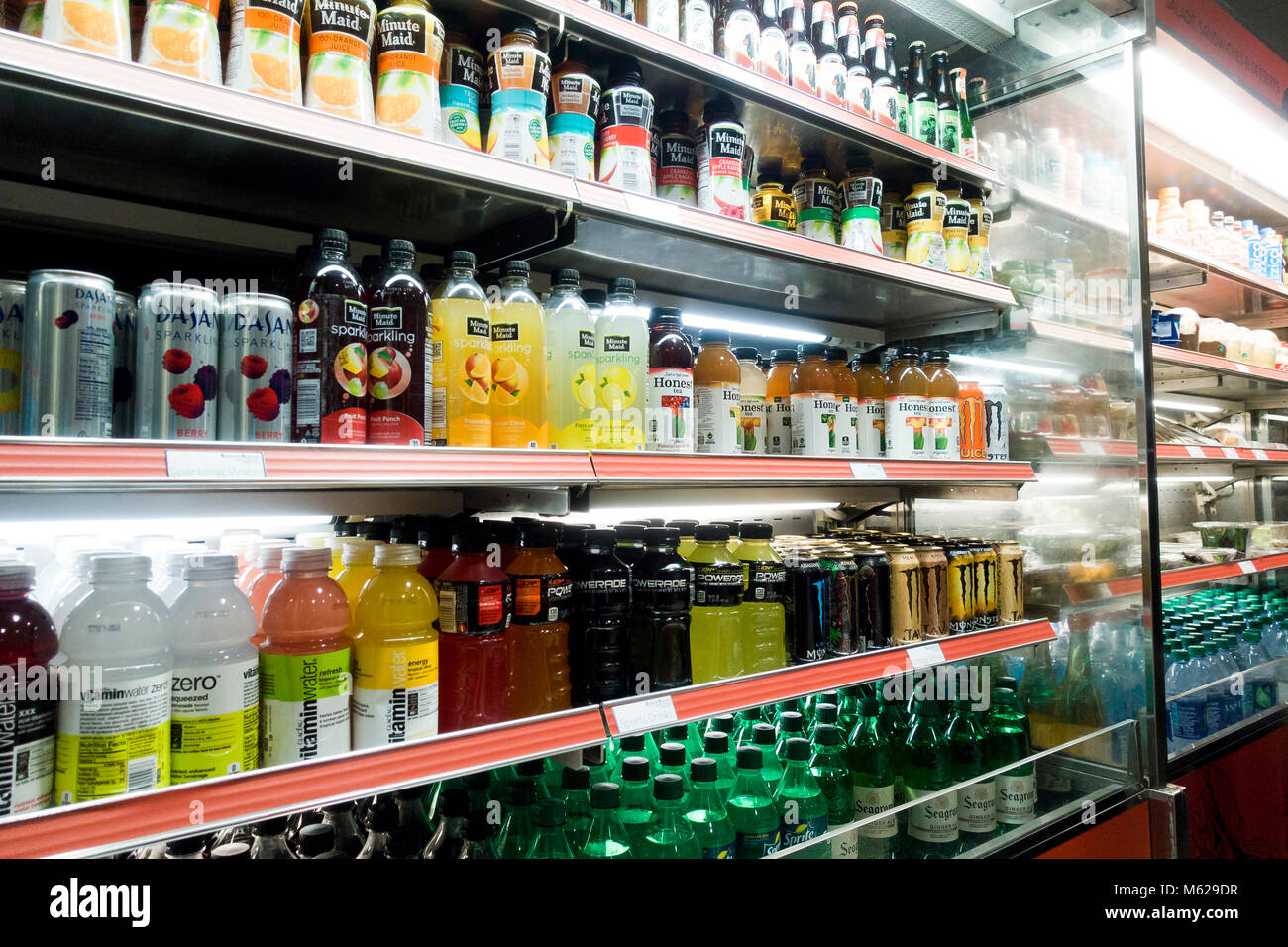 Cold carbonated drinks and bottled vitamin water in open display refrigerator at a convenience store - USA Stock Photo
