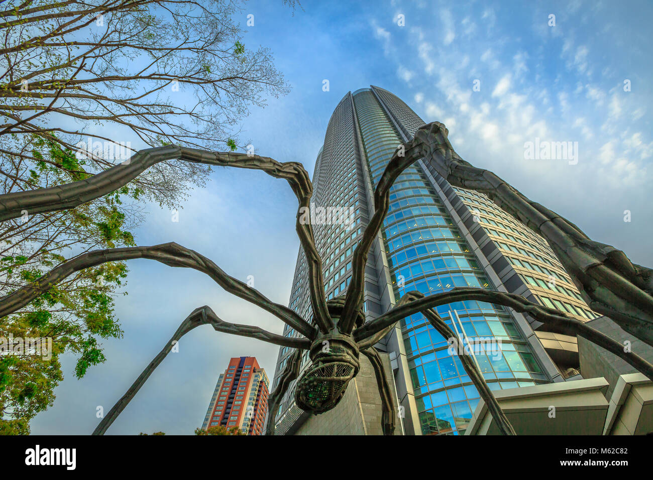 Tokyo, Japan - April 20, 2017: low angle view of Mori Tower and Maman Spider bronze sculpture inside Roppongi Hills complex in Minato District, Tokyo at sunset. Stock Photo