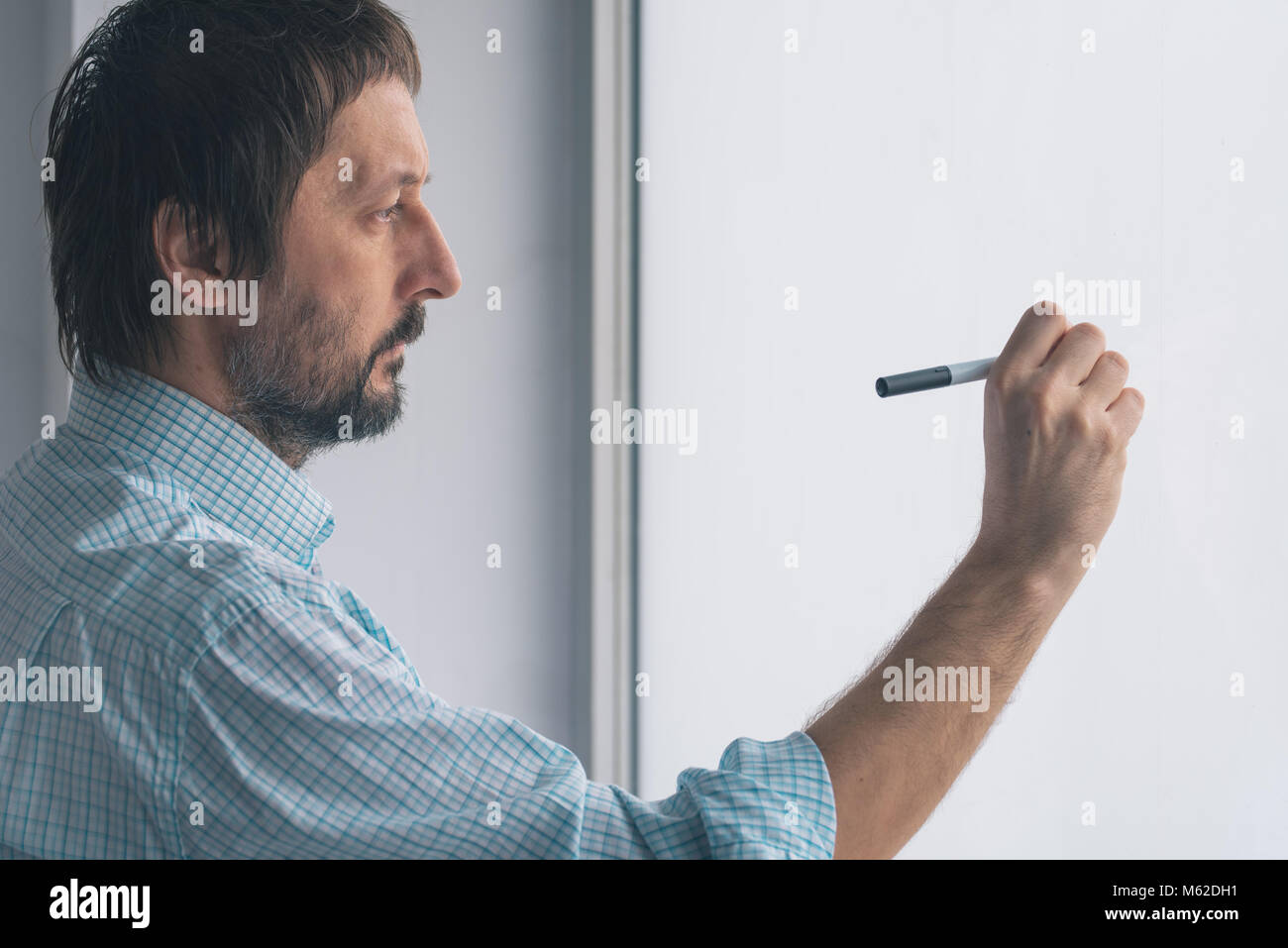 Businessman in office writing on whiteboard with marker felt pen Stock Photo