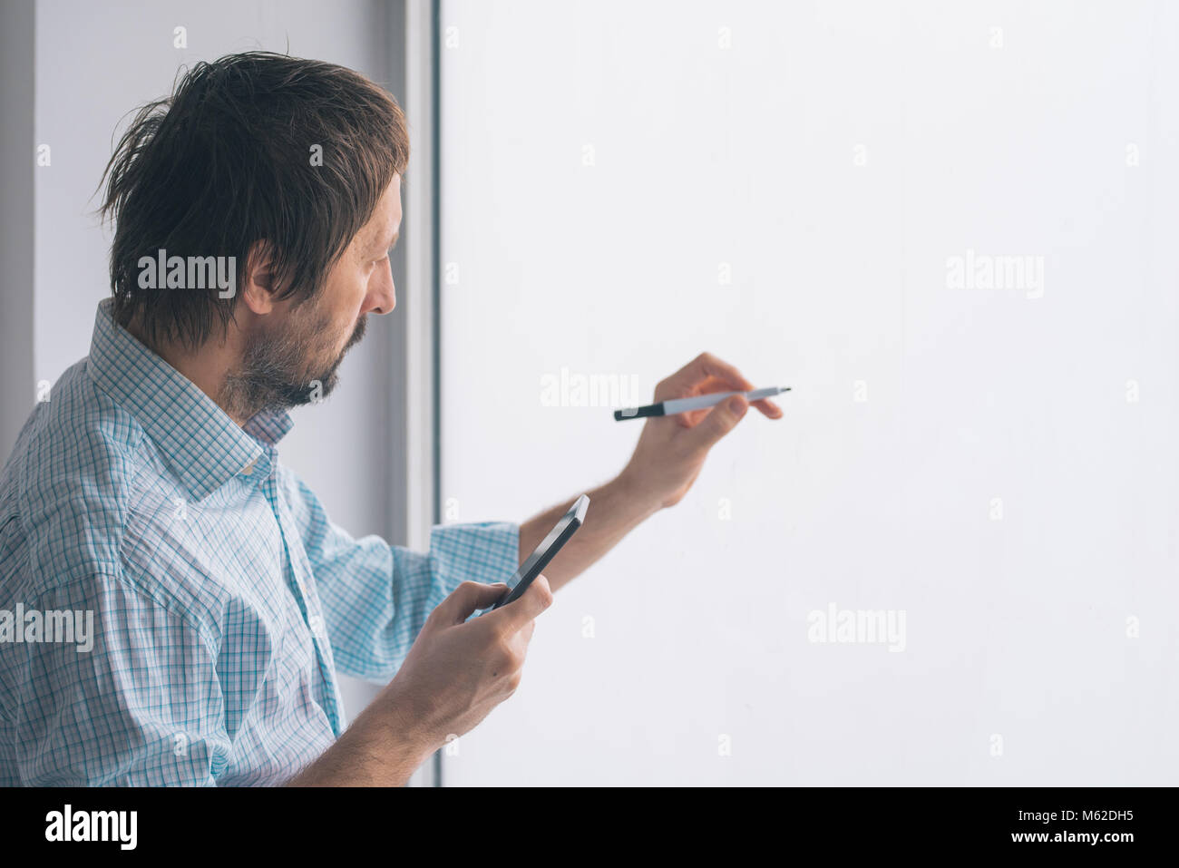 Businessman in office writing on whiteboard with marker felt pen Stock Photo