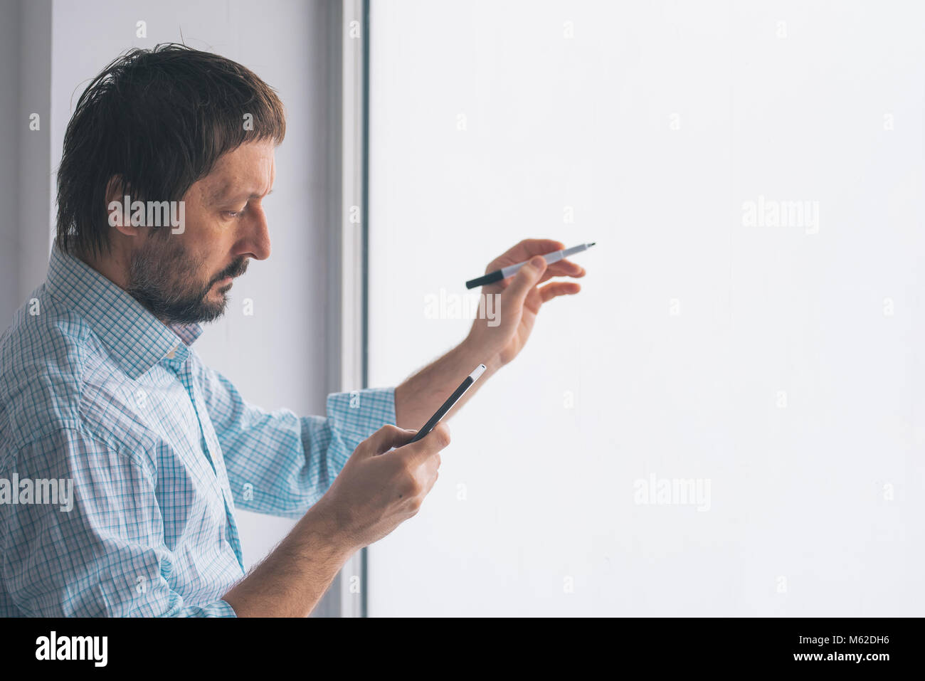Businessman in office writing on whiteboard with marker felt pen Stock Photo