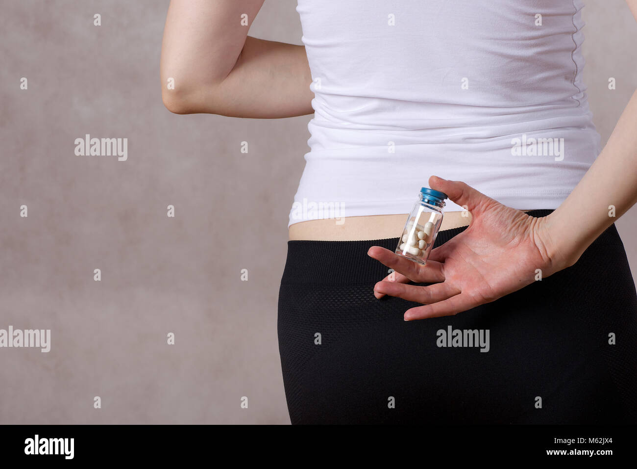 Young lady between 30 and 40 years old keeps a bottle with pills. Closeup Stock Photo