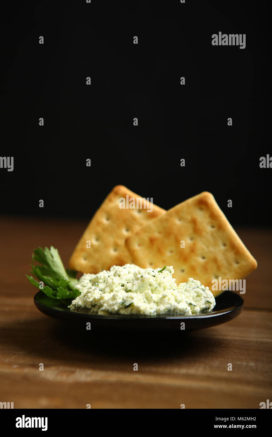 On A Dark Plate A Portion Of Cottage Cheese With Greens Is