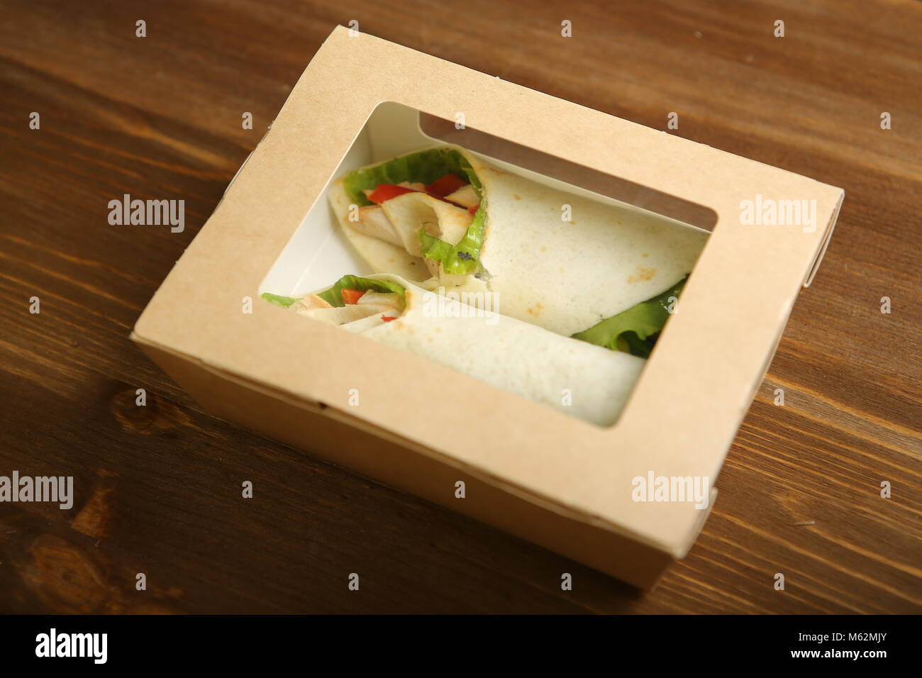 Delivery of food at home. Shaurma without sauces with chicken, pepper, salad in a cardboard container. Low-calorie lavash roll. Without frying, uncook Stock Photo