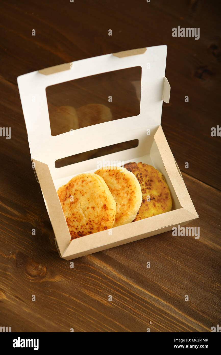 Delivery of products at home. Snack to takeaway. Cheese pancake made from cottage cheese in a disposable cardboard box. Correct, low-calorie food Stock Photo