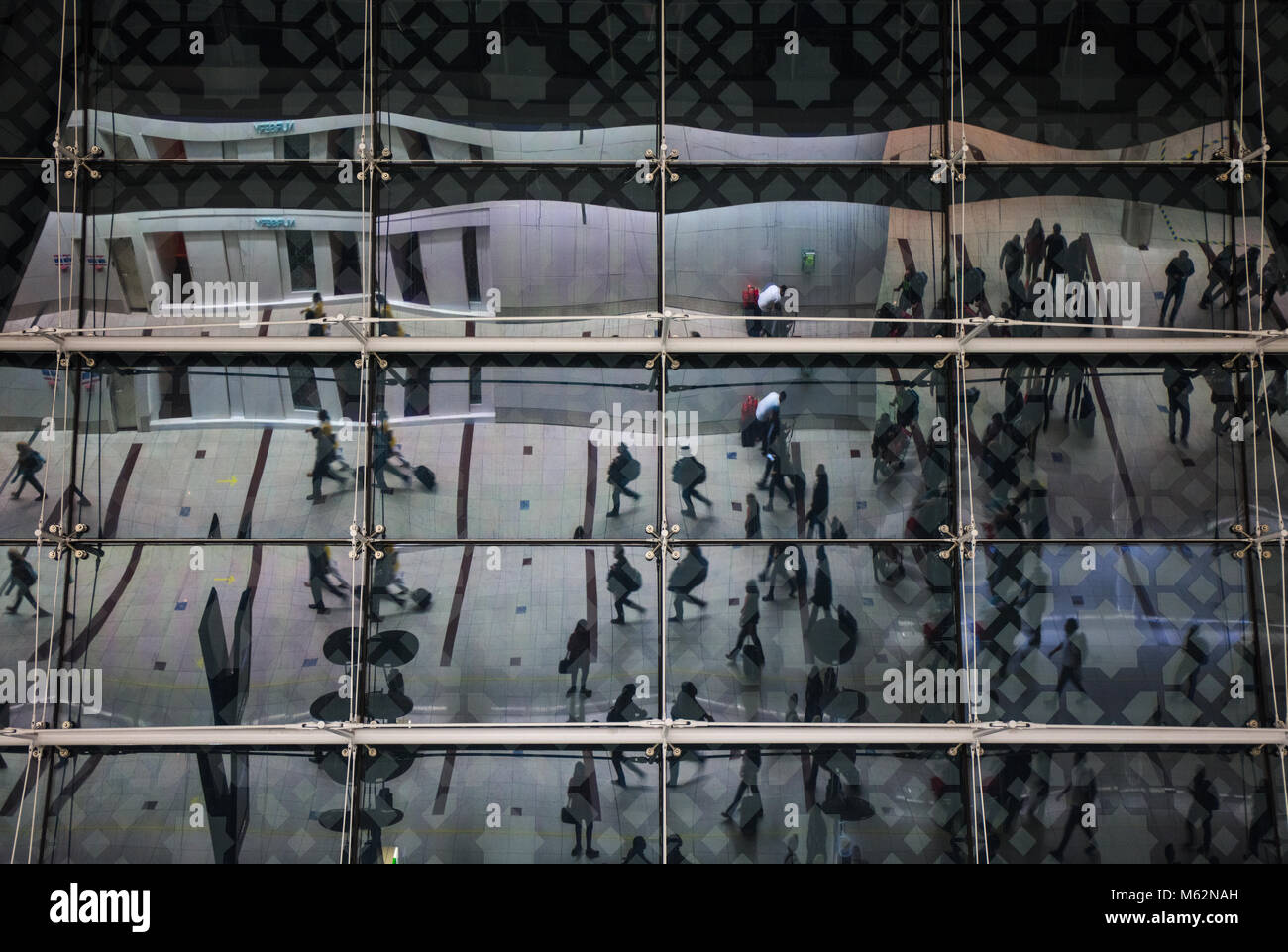 Crowd of passengers reflected in the windows of the Dubai International airport. United Arab Emirates. Stock Photo