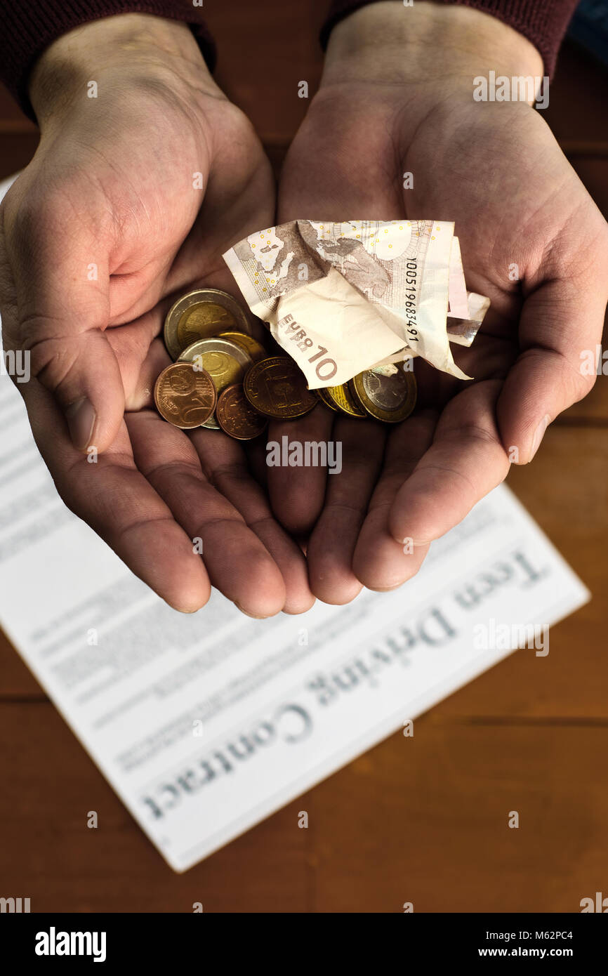 A small handful of small money in the collected male palms on the background of the contract. Stock Photo