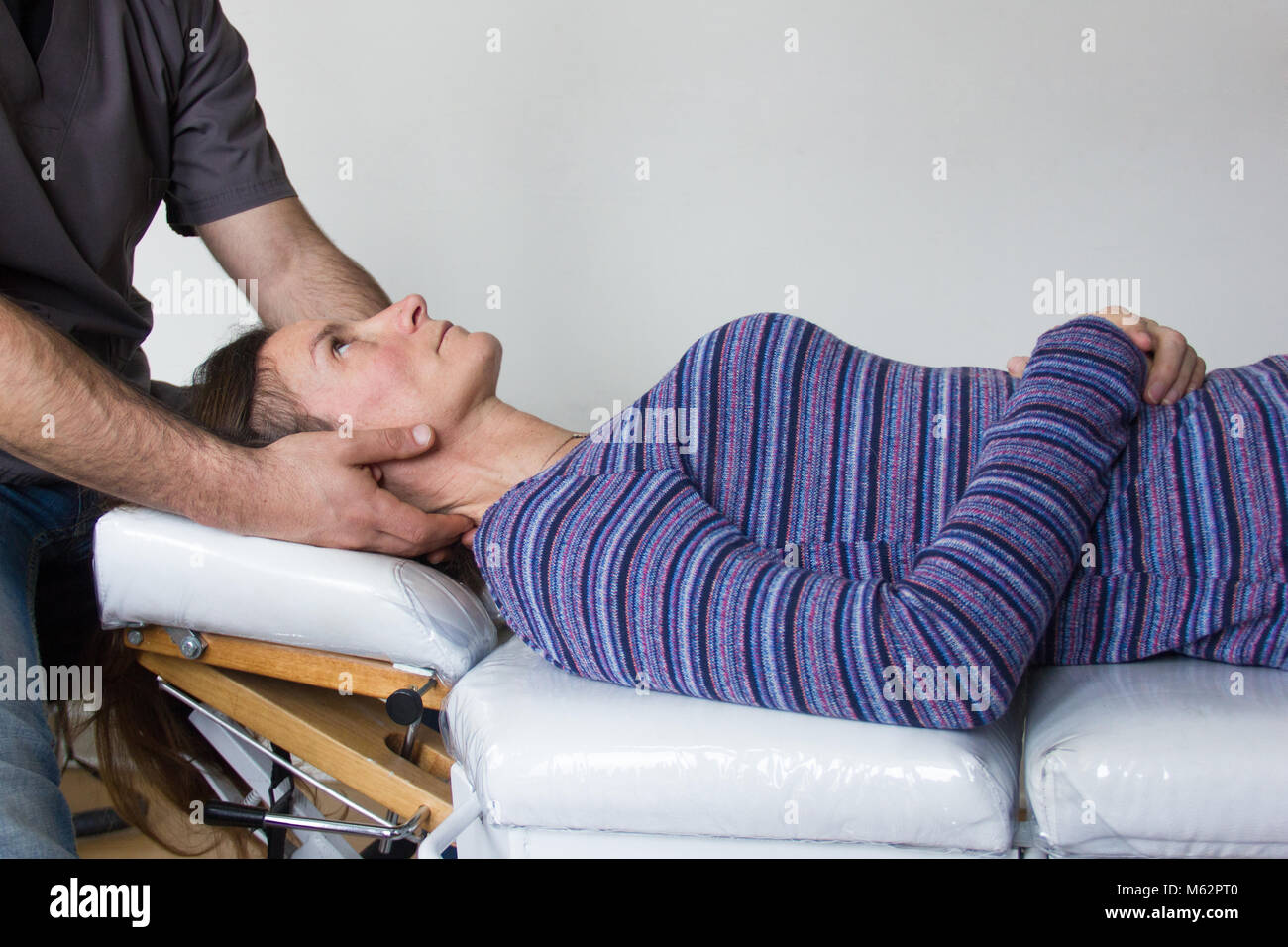 A man is a chiropractor doing a massage to a woman in the neck and trapezius  muscles in his office Stock Photo - Alamy