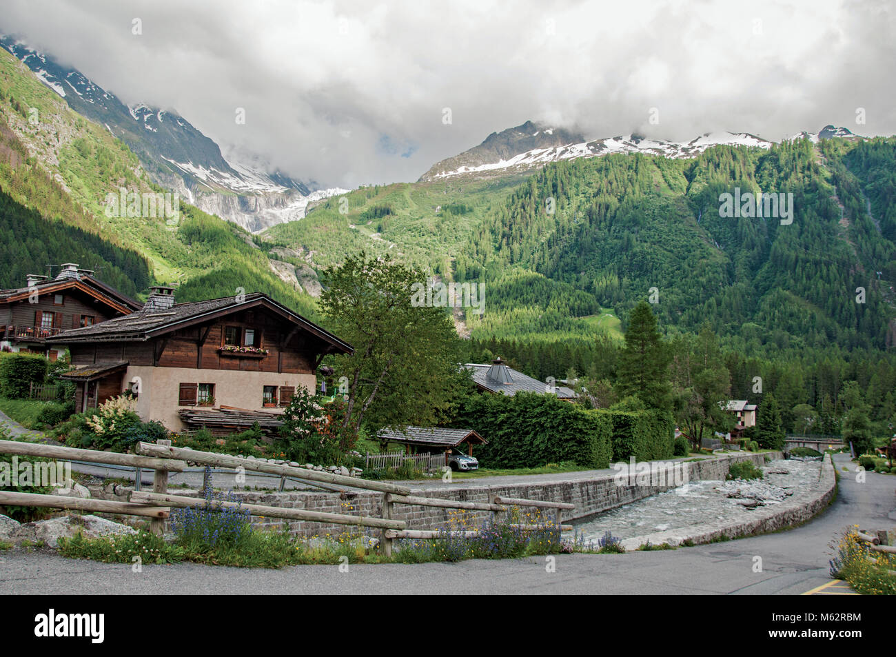 View of creek, houses and alpine landscape in a cloudy weather at