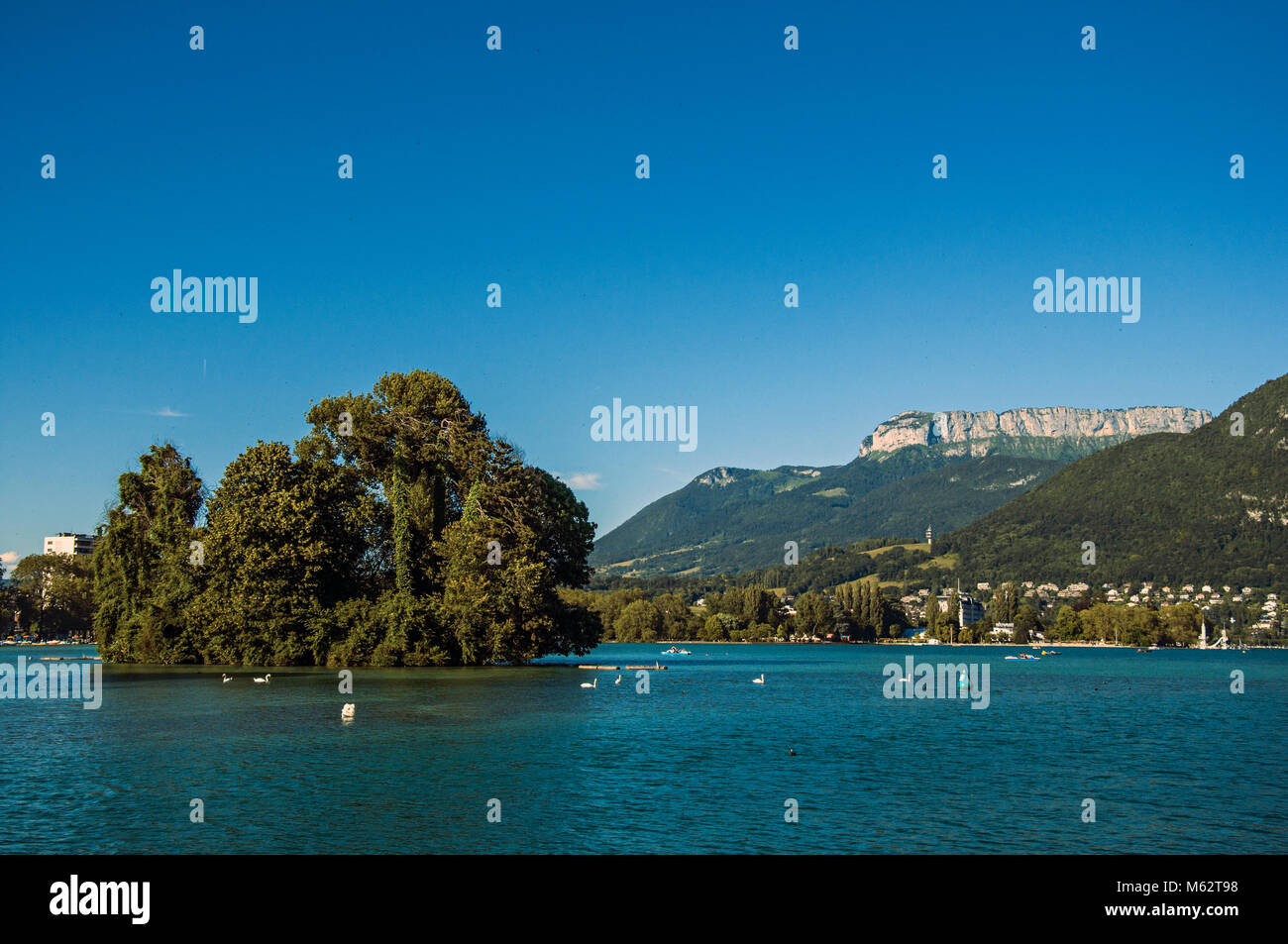 View of Annecy lake, with island, vegetation, mountains and blue sky in ...
