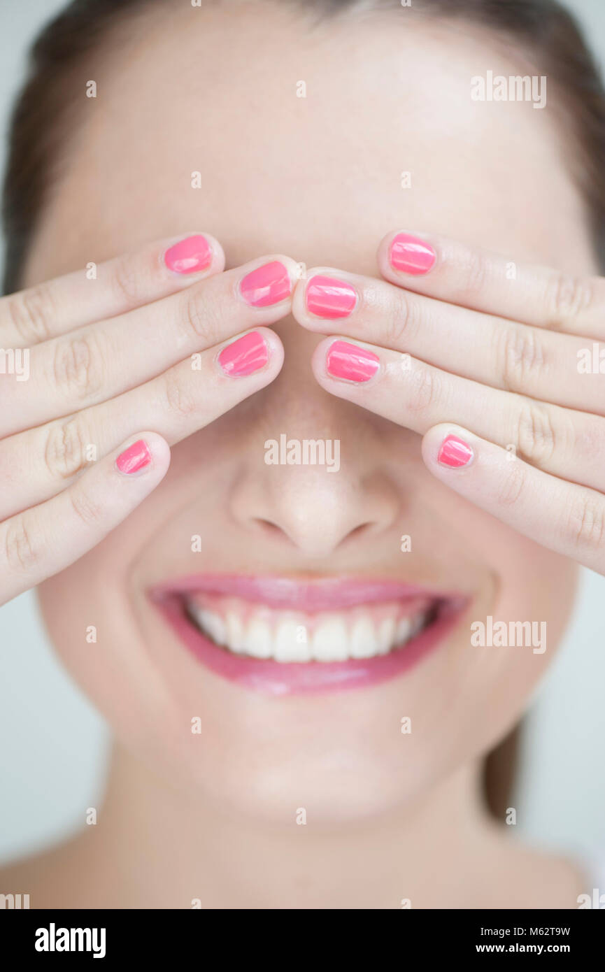 Smiling woman covering eyes with hands Stock Photo
