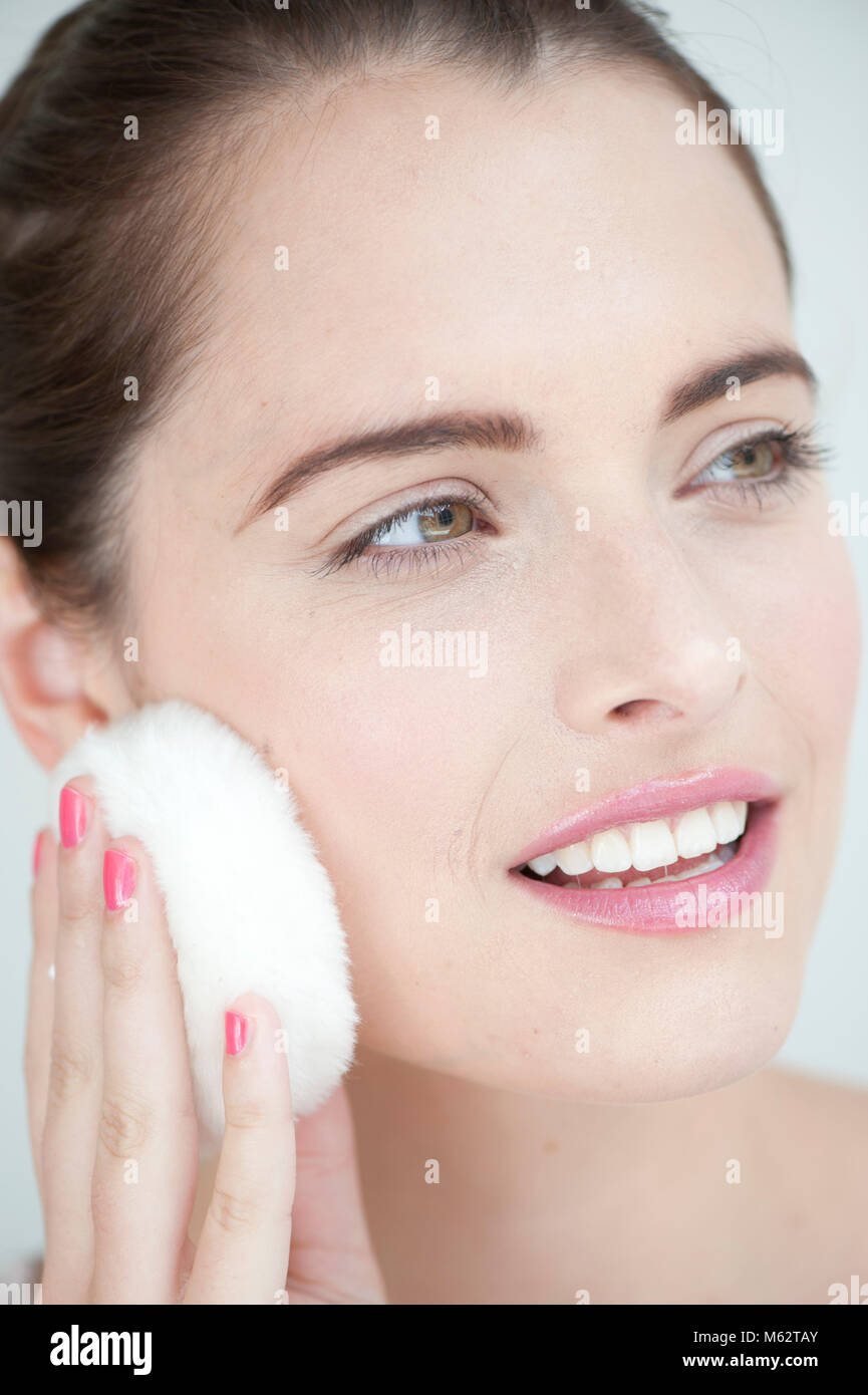 Woman with powder puff to cheek. Stock Photo