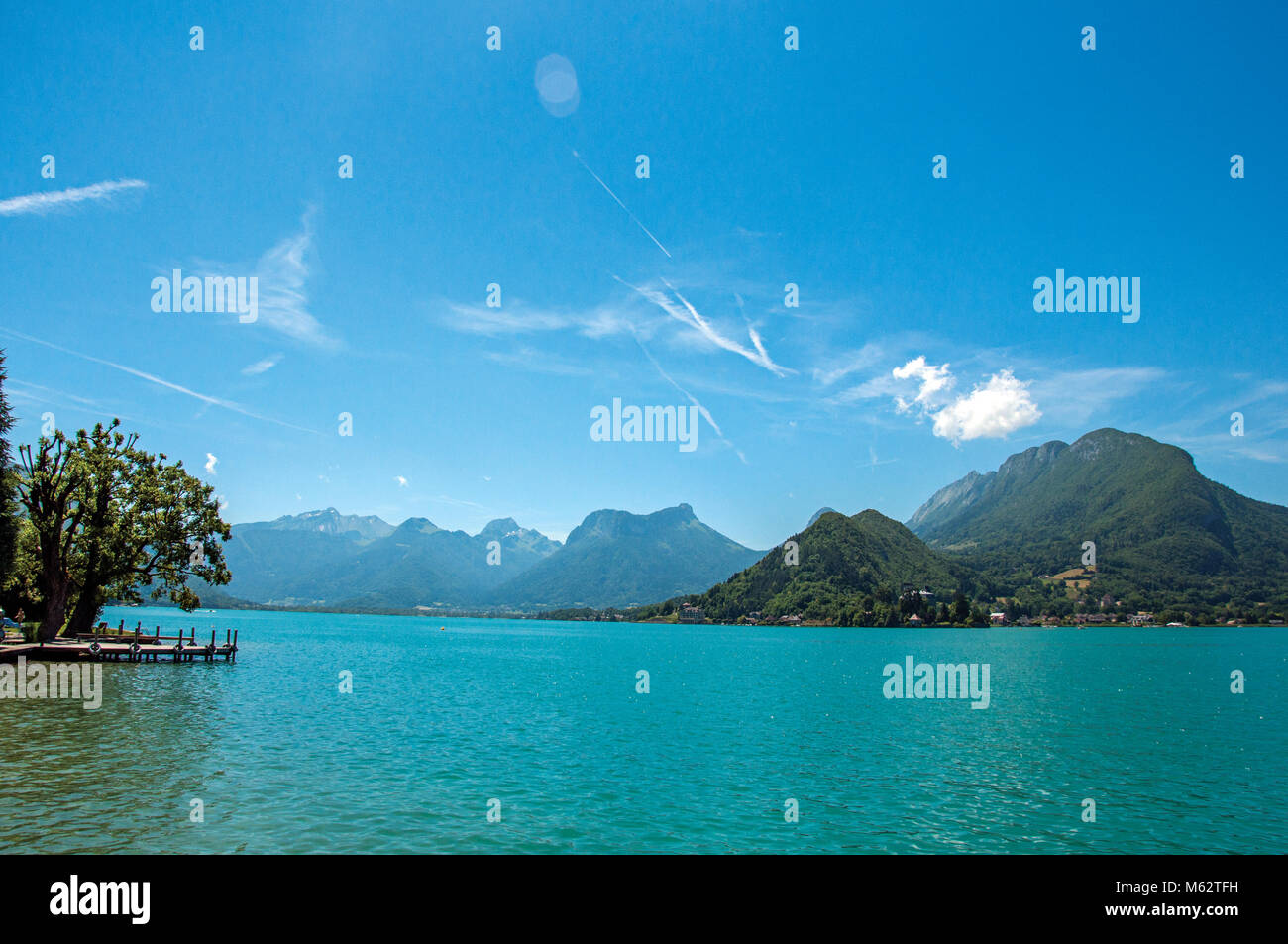 Pier with flowers on the Annecy Lake with blue sky mountains landscape ...