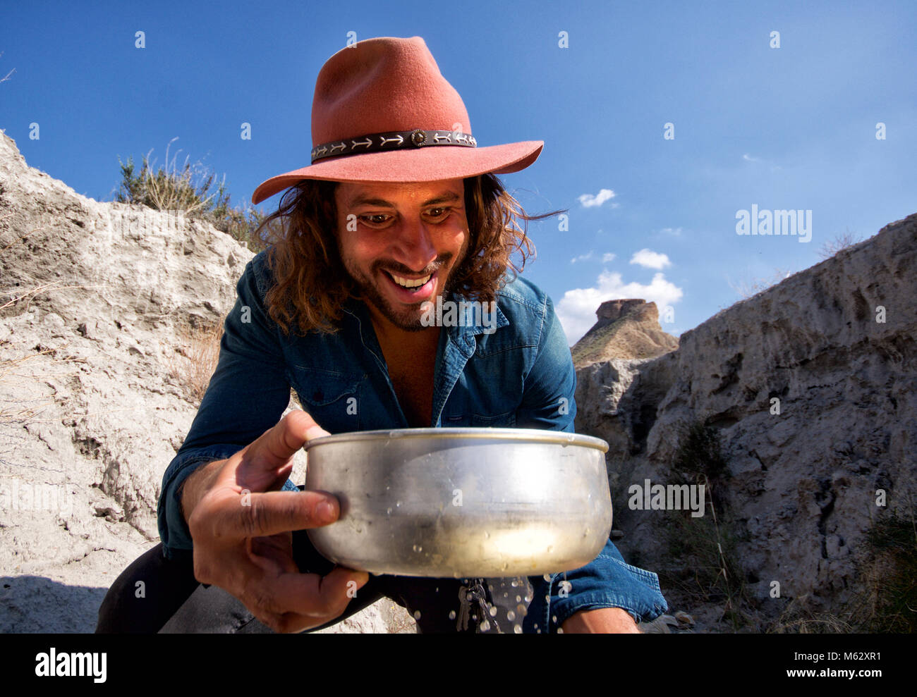 Cowboy gold panner happy at finding gold which reflects on his face Stock Photo