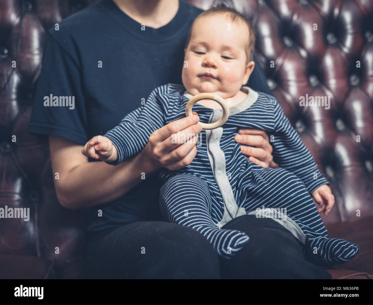 A mother is offering her baby a teething ring to chew on Stock Photo