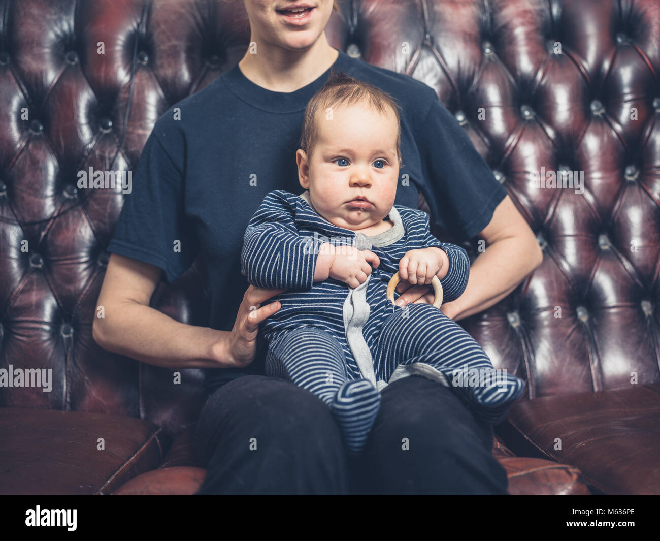 A mother and her baby are sitting on the sofa watching television Stock Photo