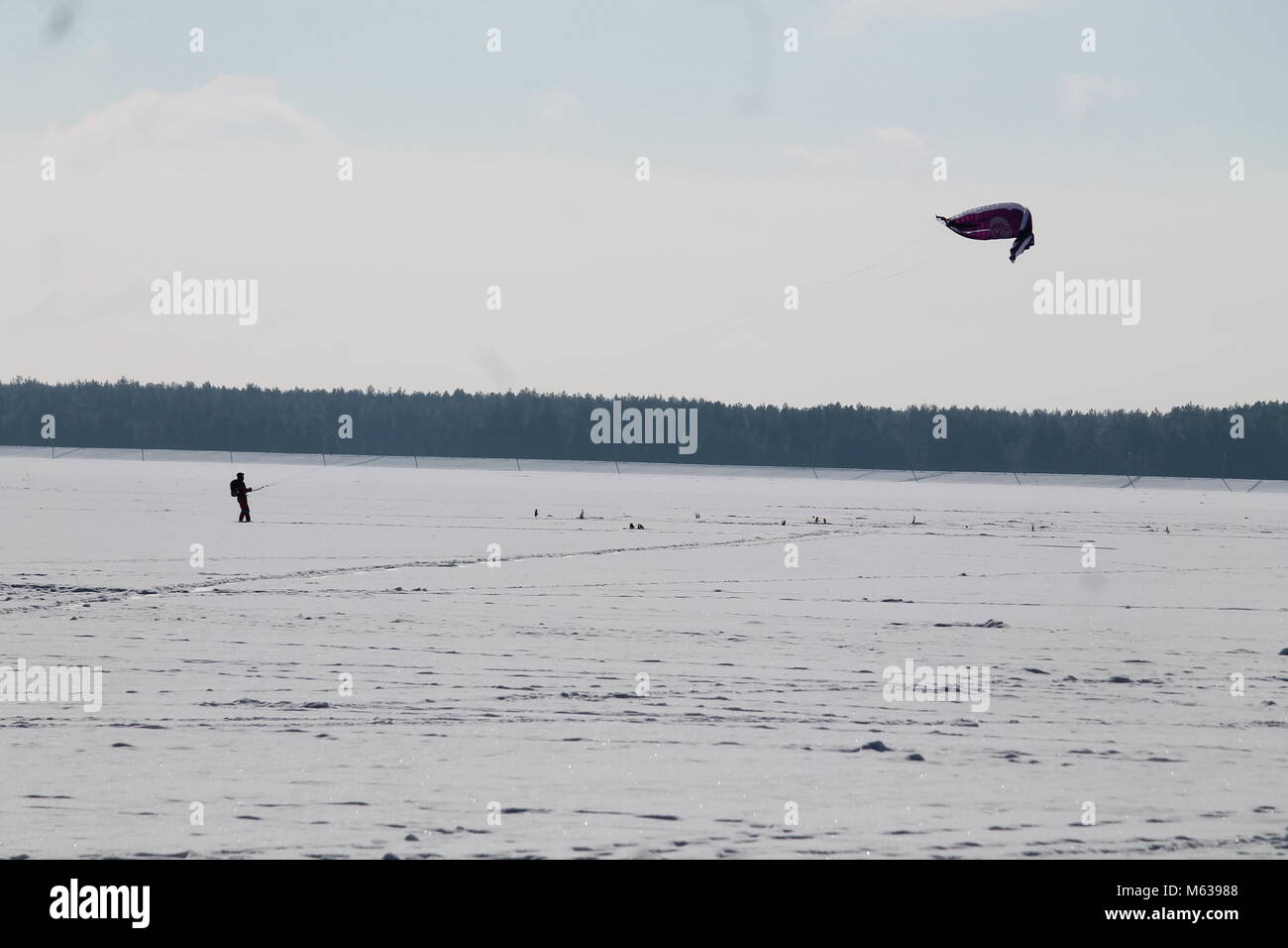 brave man under parachute on snowboard training on the surface of frozen sea in cold winter day Stock Photo