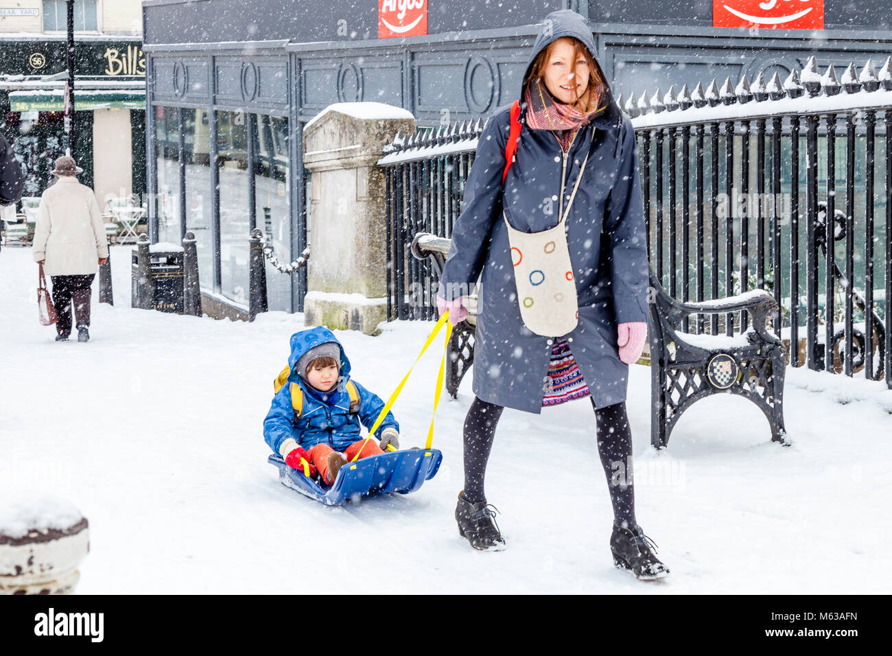 A local woman pulling a child on a sledge, High Street, Lewes, East Sussex, UK Stock Photo