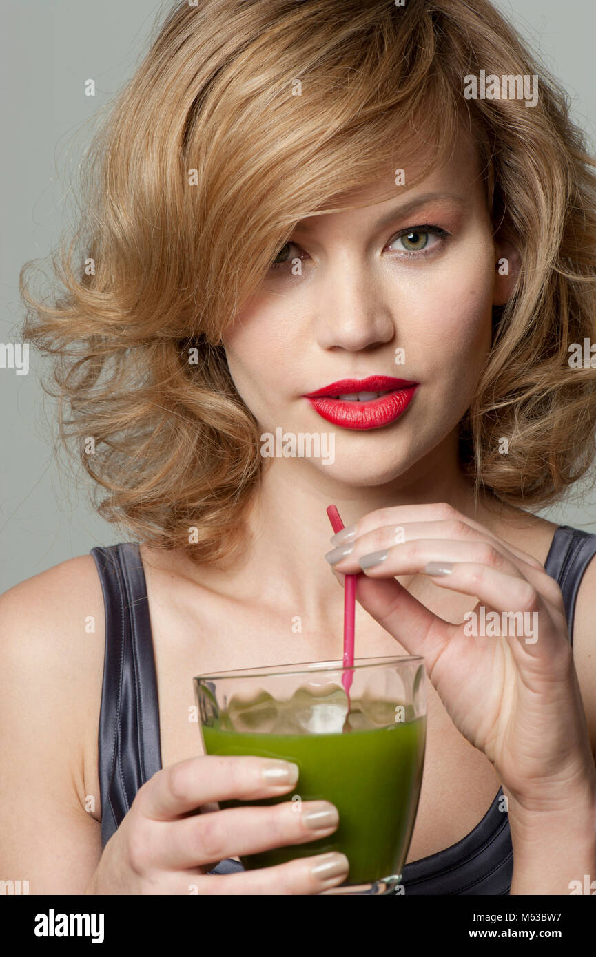 Woman drinking green juice with a straw Stock Photo